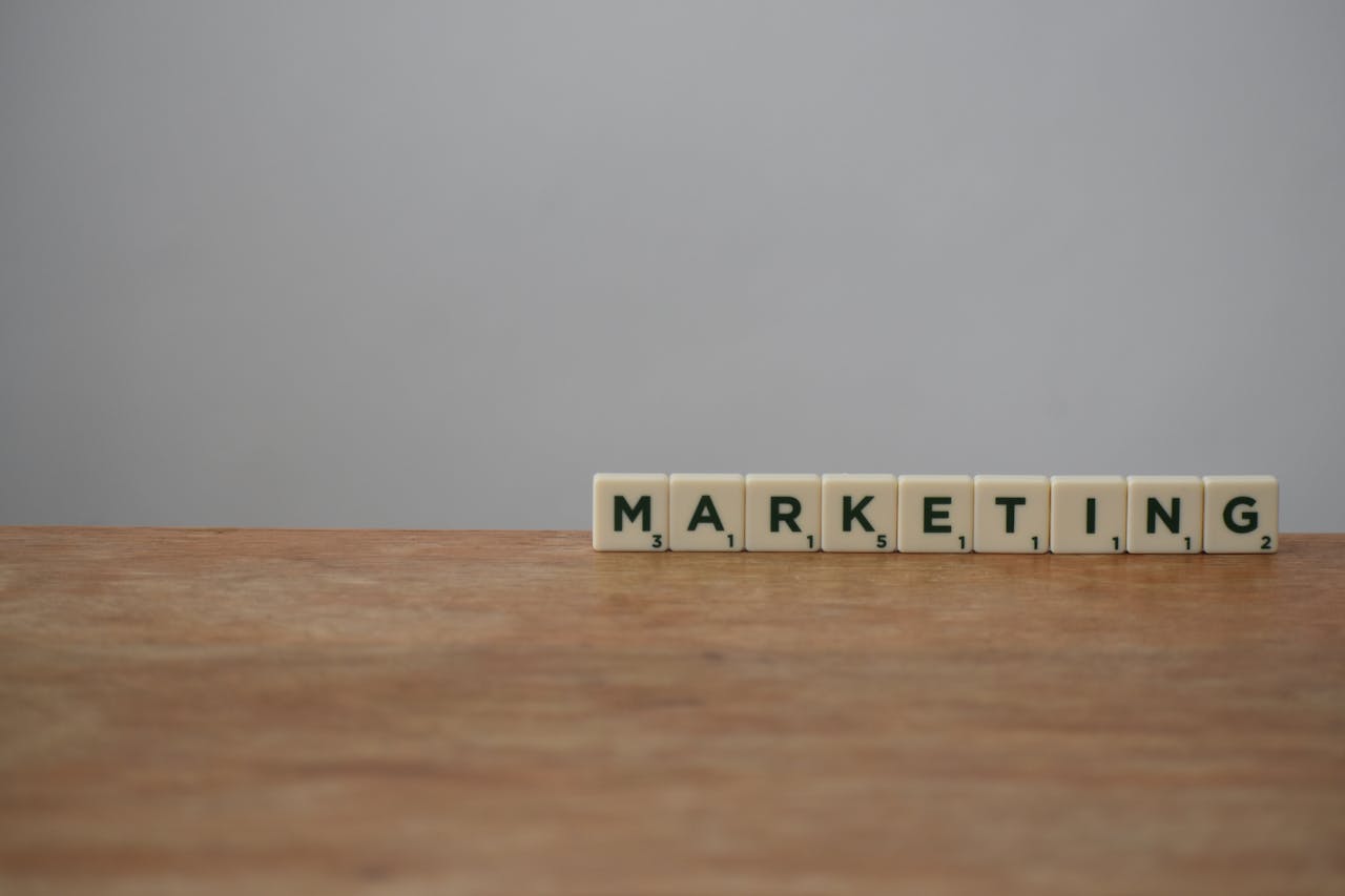 Scrabble tiles spelling MARKETING on a wooden table with a neutral background.